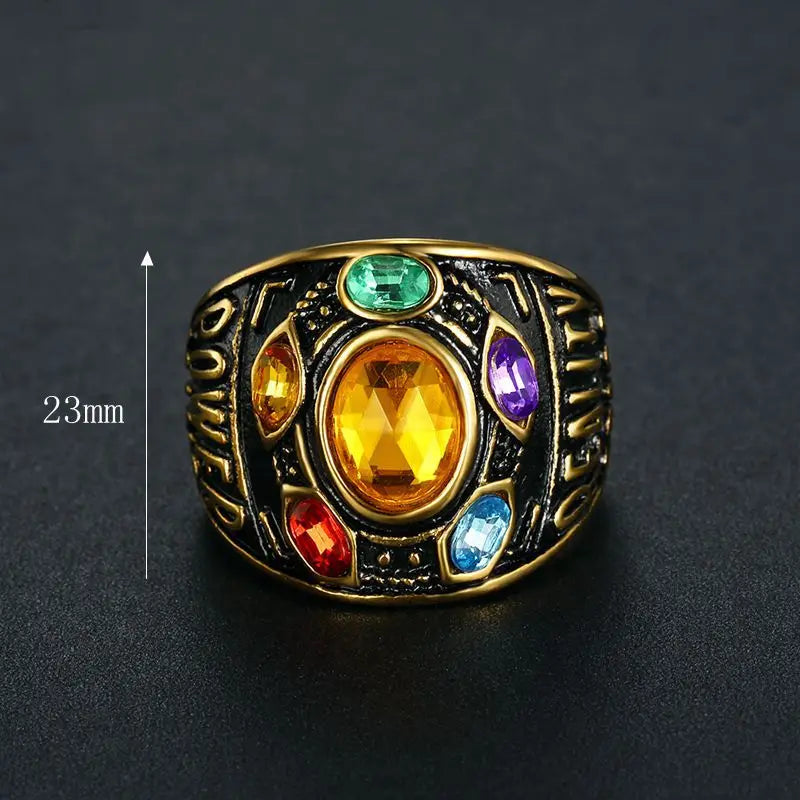Ring with colored gemstones and 'Avengers' text on a dark background