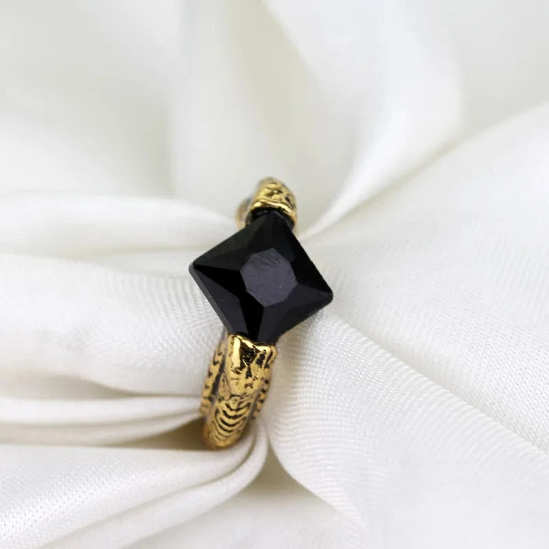 Top-down view of the Gaunt family ring replica featuring a square-cut black stone and textured gold snake-scale band.