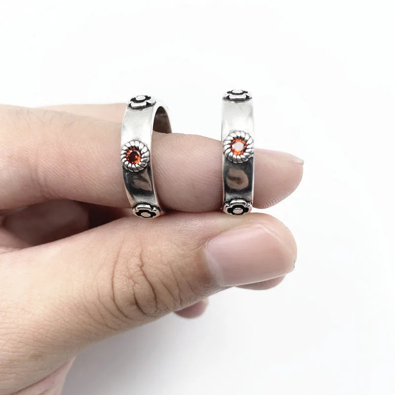 Silver couple rings with gemstones held between fingers on a white background