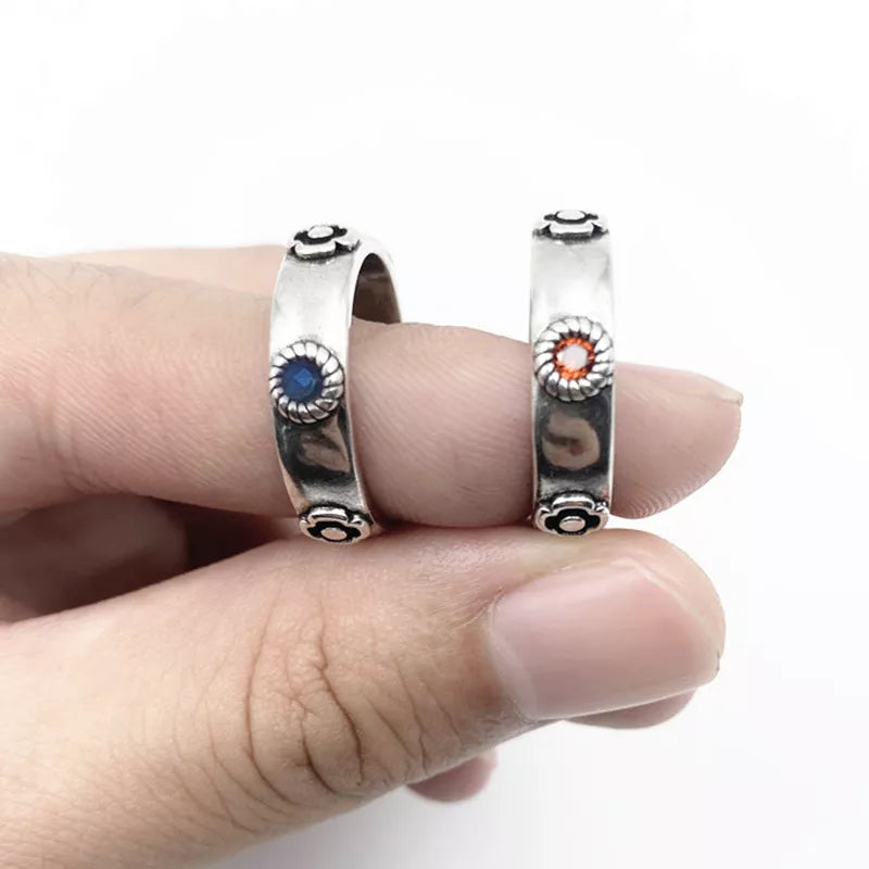 Two silver rings with colorful stones on a finger against a white background