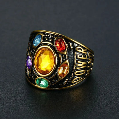 A gold ring with "POWER" engraved on the side, featuring a large yellow central gem surrounded by smaller red, green, blue, and purple gems.