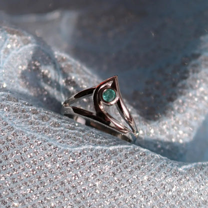 bronze ring from valorant video game with a green gemstone on a textured silver surface