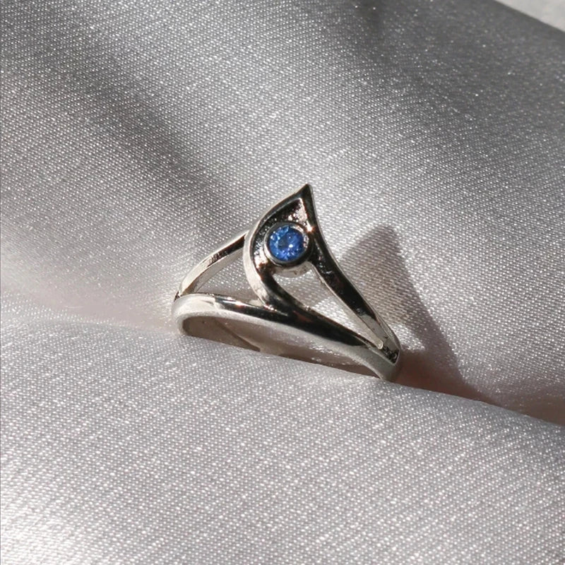 Silver ring with a blue gemstone on a silver fabric background